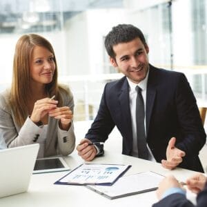 Business professionals discussing project strategy around a conference table with documents and laptops.